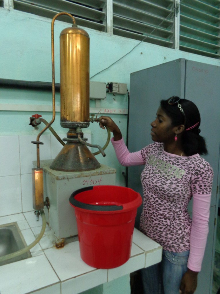 Marileyxis muestra el destilador de agua, uno de los tantos equipos que arreglaron con piezas viejas y con el tesón de los estudiantes. Foto: De la autora