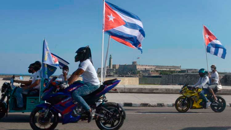 Motociclistas conducen ondeando banderas cubana mientras recorren el emblemáticos Malecón de La Habana en una singular caravana que demandó el fin del bloqueo que desde hace más de medio siglo mantiene Estados Unidos contra la isla, en La Habana, el 28 de marzo de 2021. Foto: Joaquín Hernández Mena/Trabajadores